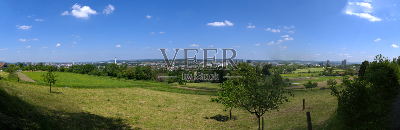 美丽的全景景观在瑞士小镇与农田在明亮的阳光前景。照片摄影图片