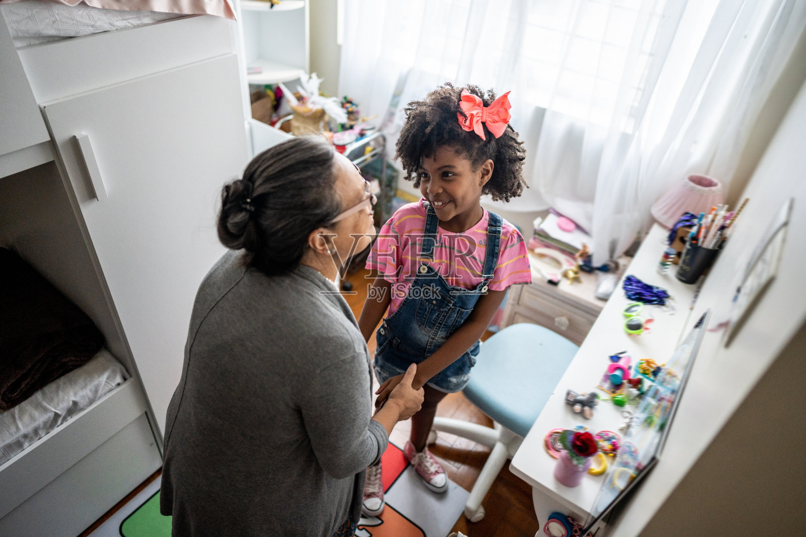 女孩在家里的卧室里和她的祖母说话照片摄影图片