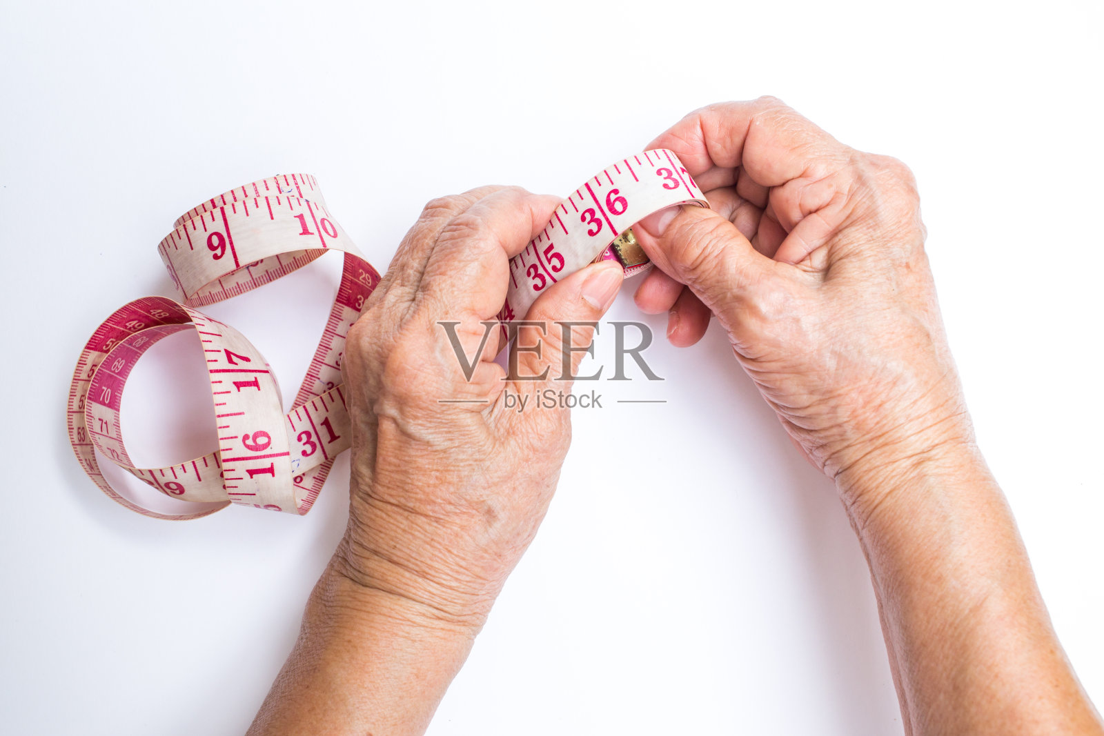 高级妇女的手卷卷尺孤立在白色的背景，关于裁缝照片摄影图片