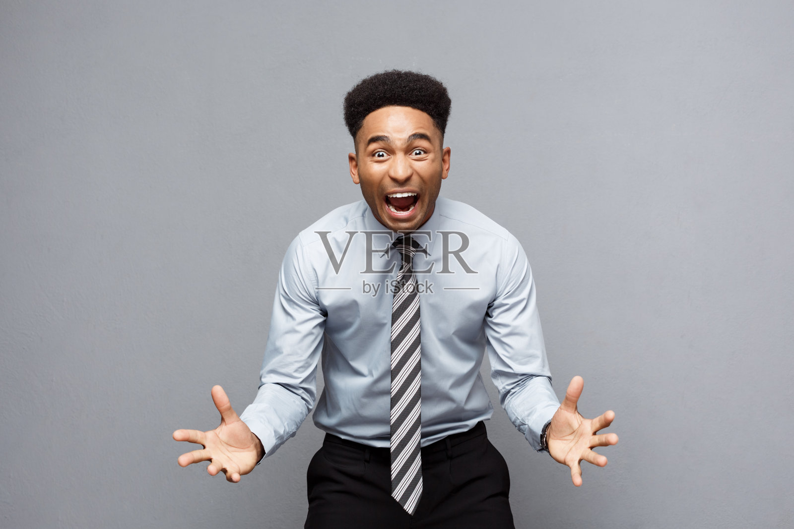 商业理念——自信开朗的年轻非洲裔美国人在灰色背景下失望地举手。照片摄影图片