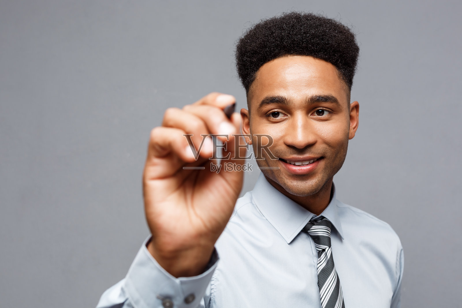 商业理念——自信的非裔美国人业务经理准备在办公室的虚拟板或玻璃上写字。照片摄影图片