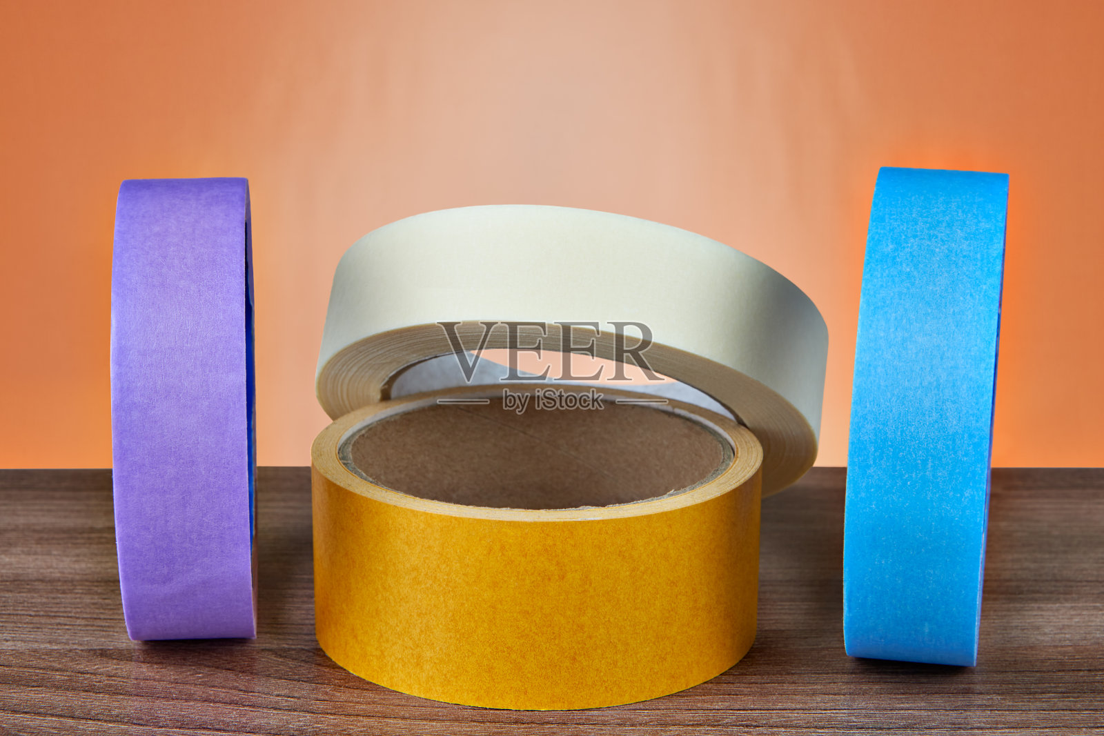 橙色背景上的几卷彩色胶带。照片摄影图片