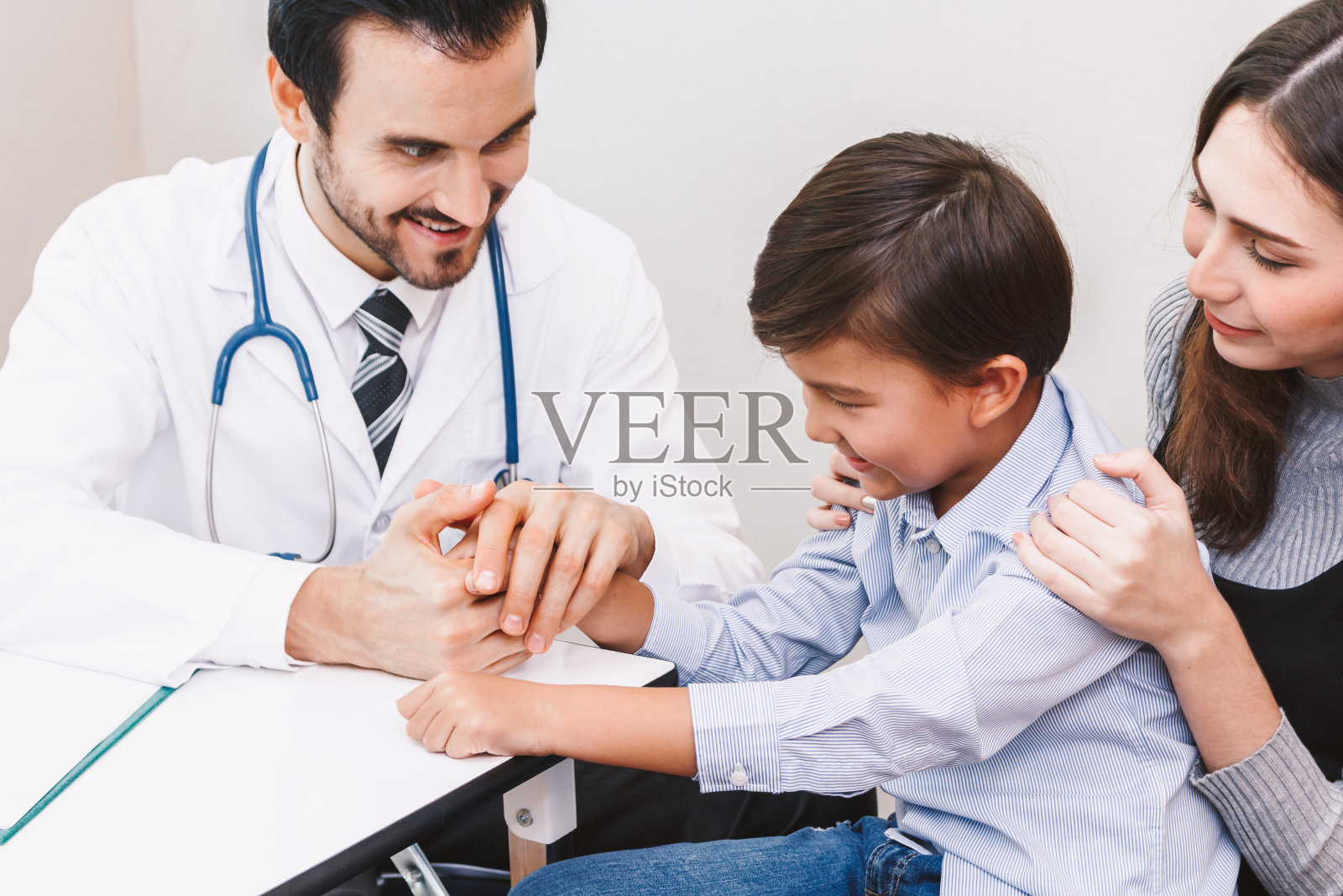 医生在医院的手术台上小心翼翼地牵着小男孩的手。医疗保健和医药照片摄影图片