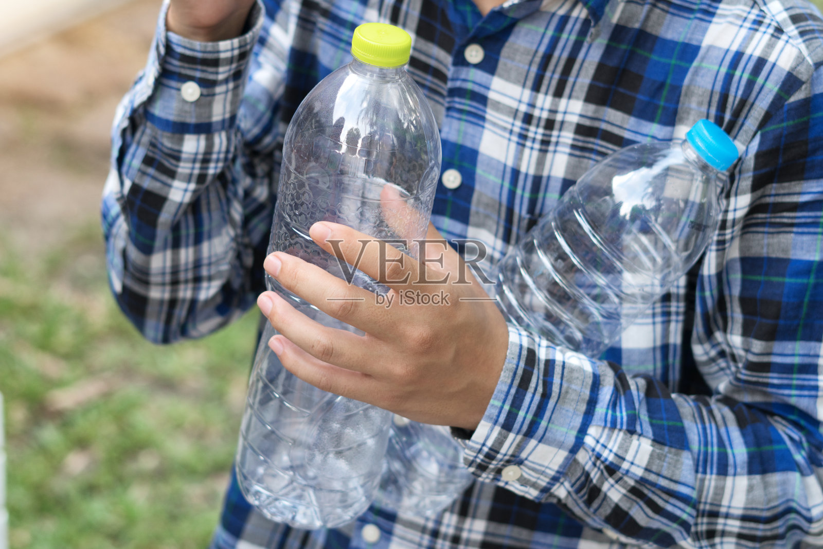 手持可回收的塑料瓶在垃圾桶与夕阳灯照片摄影图片