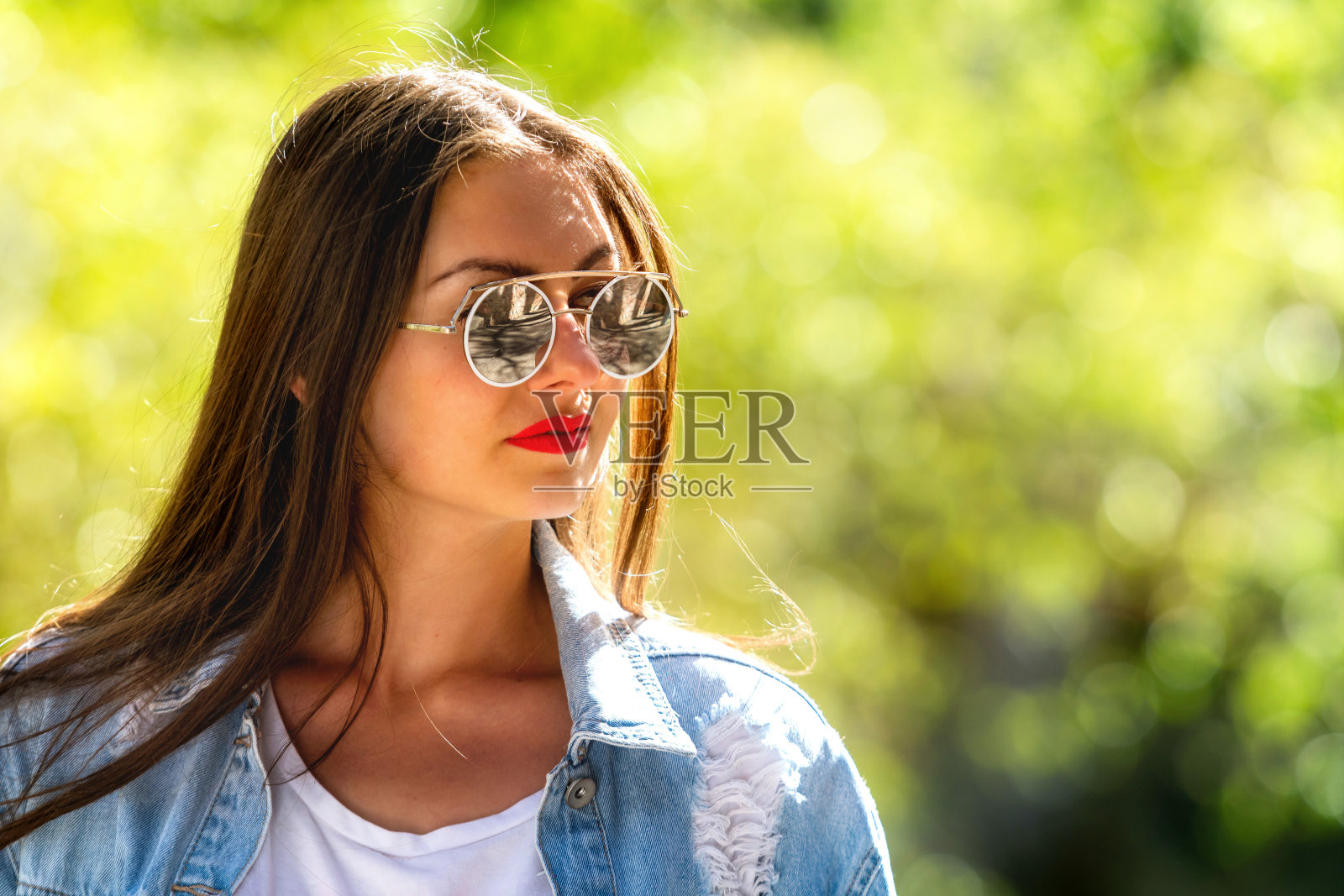 戴着太阳镜的年轻女性的户外情绪肖像。柔和的背景。照片摄影图片