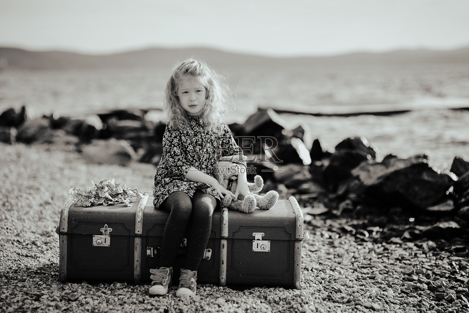 悲伤的孩子坐在手提箱上玩玩具照片摄影图片