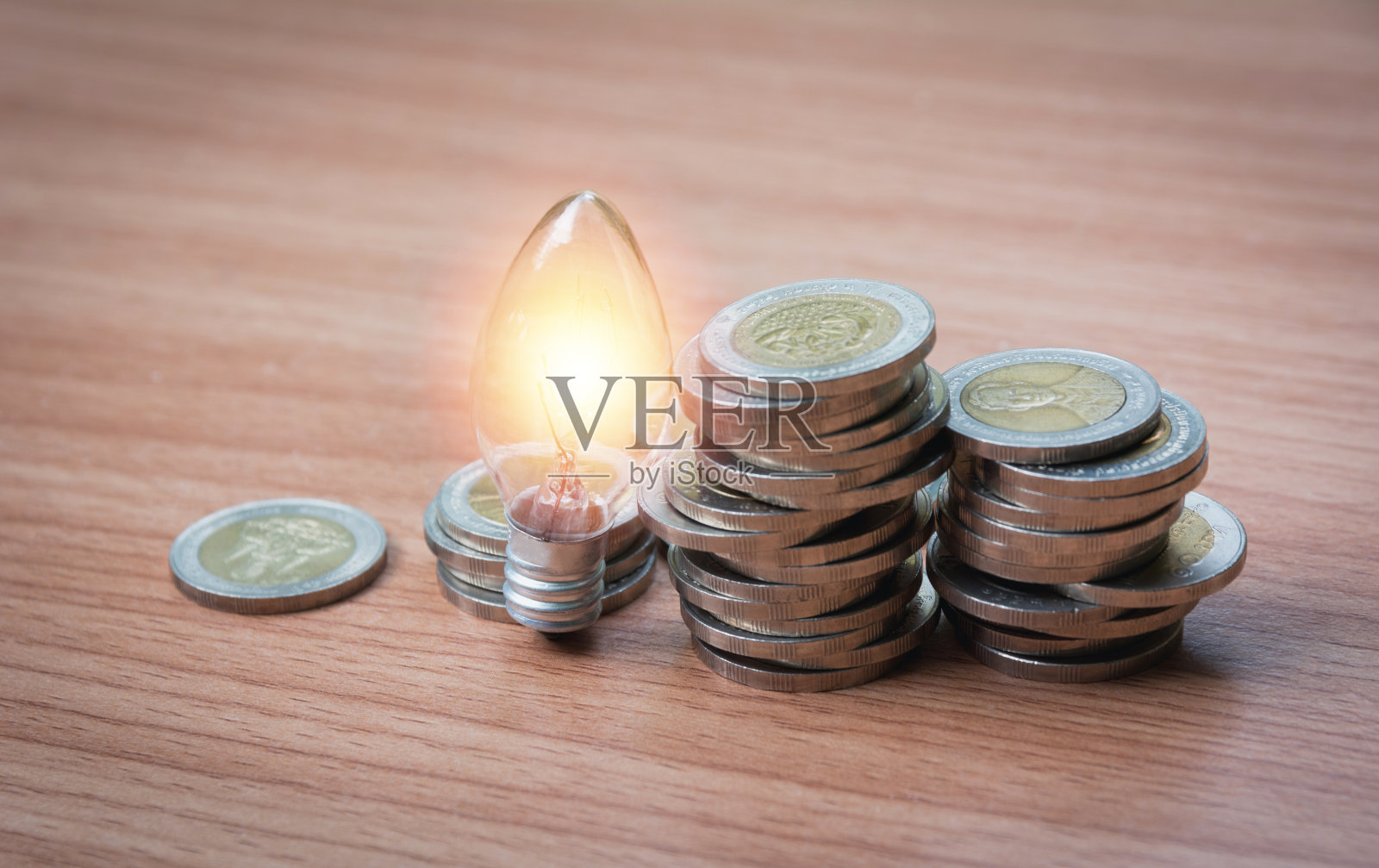 节能灯泡和树木生长在成堆的硬币在自然背景。储蓄、会计和财务概念。照片摄影图片