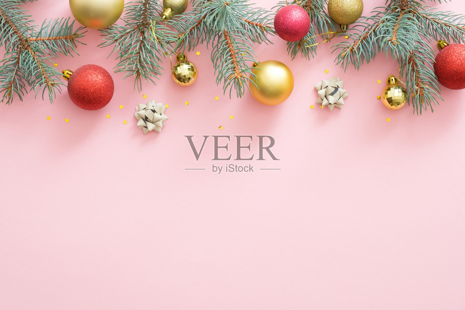 圣诞框架由明亮的闪闪发光的小玩意，冷杉树枝，装饰在粉红色的粉彩背景。圣诞派对邀请卡模型，明信片模板。平躺，俯视图，头顶照片摄影图片