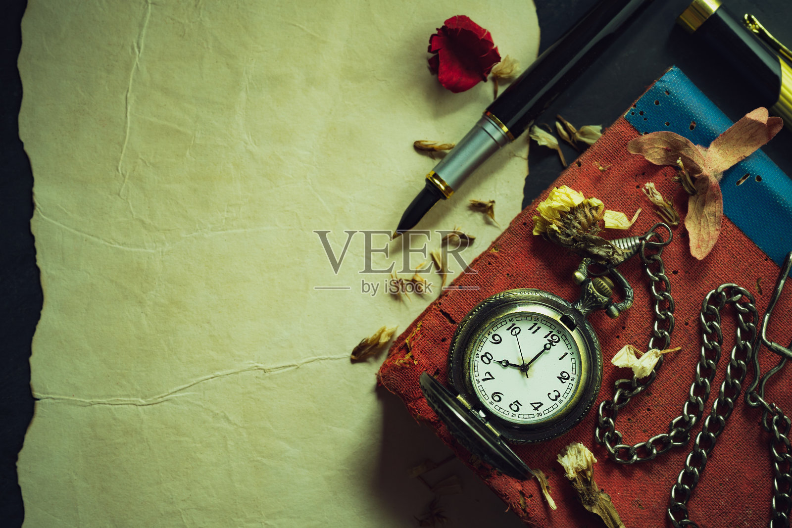 古董怀表和旧书上的铜笔。照片摄影图片