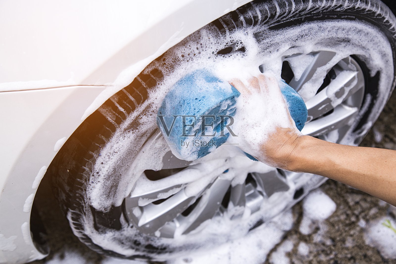 女性双手拿着蓝色海绵洗车。概念洗车清洁。照片摄影图片