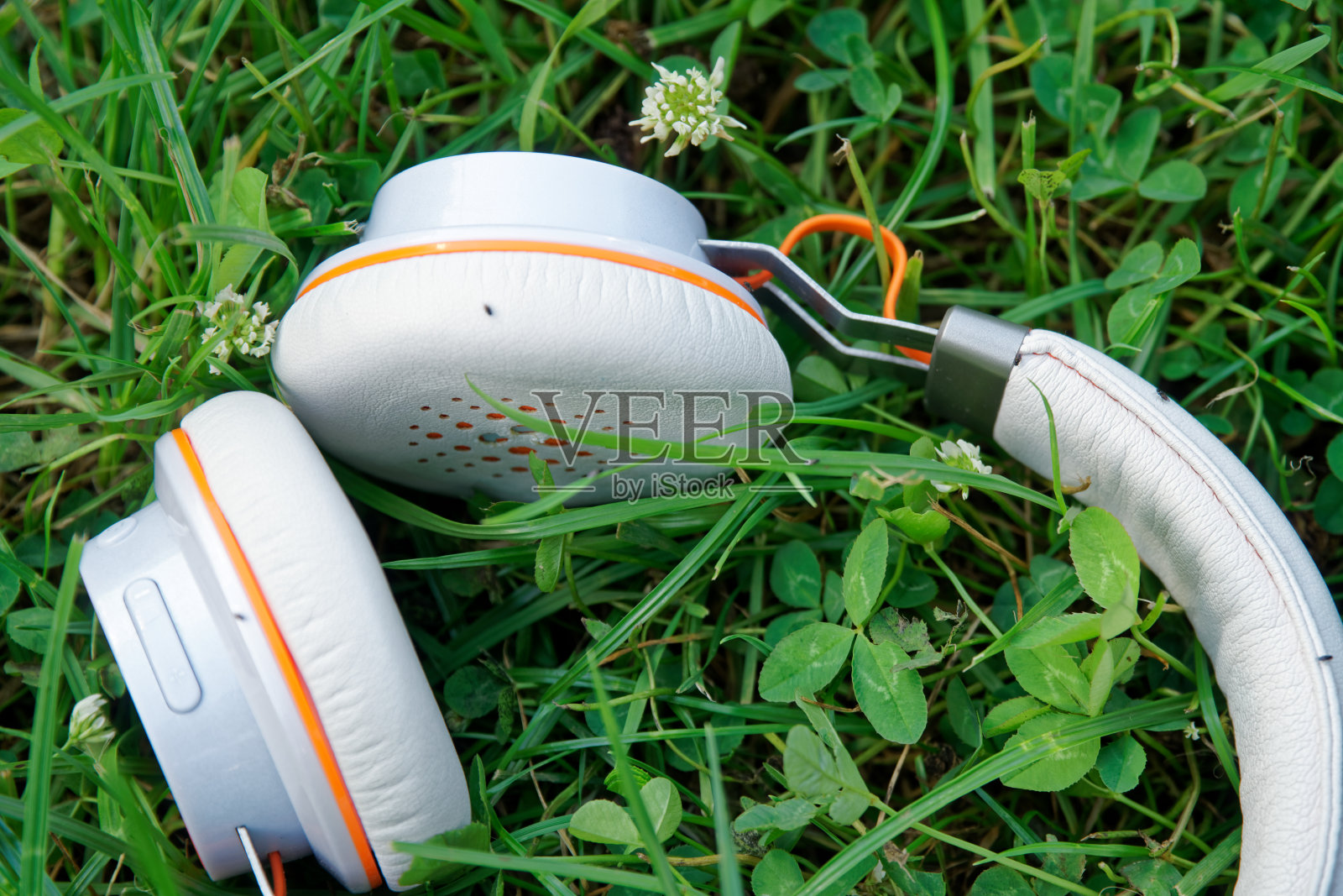 耳机躺在阳光明媚的绿草地上，经营理念照片摄影图片