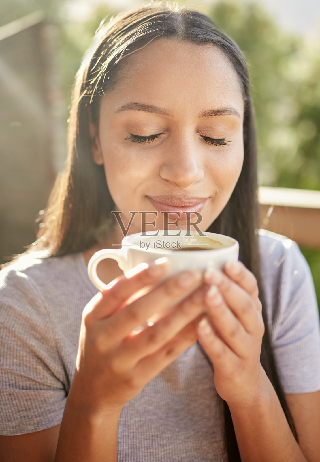 一个迷人的年轻女子独自坐在外面，享受着一杯咖啡照片摄影图片