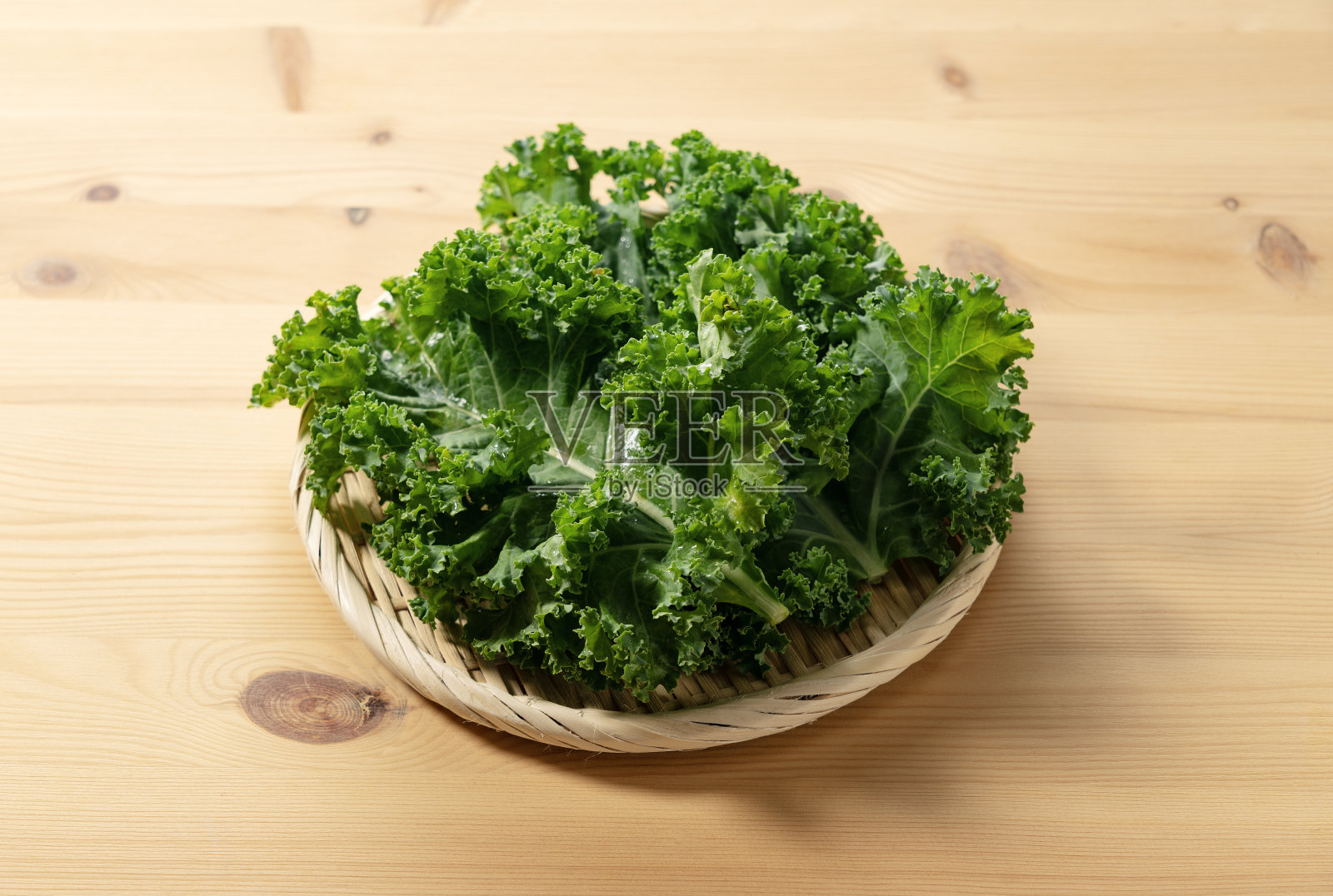 羽衣甘蓝放在木质背景上的滤锅里。照片摄影图片