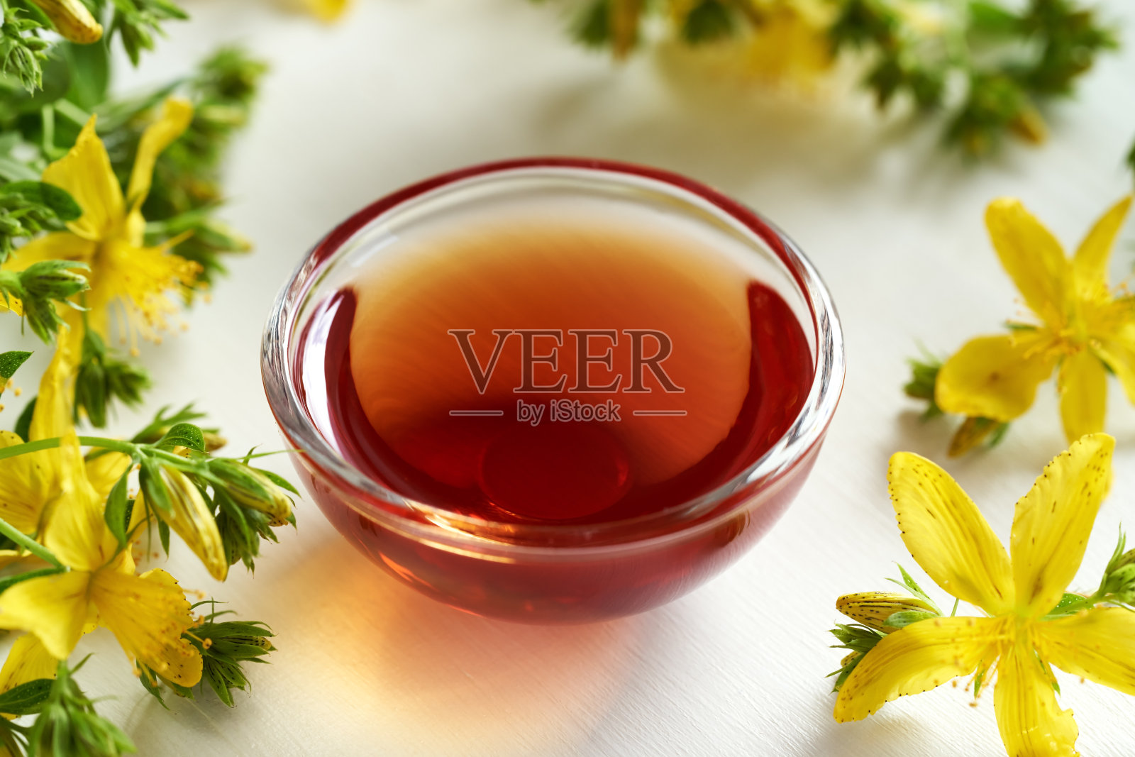 装在玻璃瓶里的圣约翰草油和新鲜的金丝桃花照片摄影图片