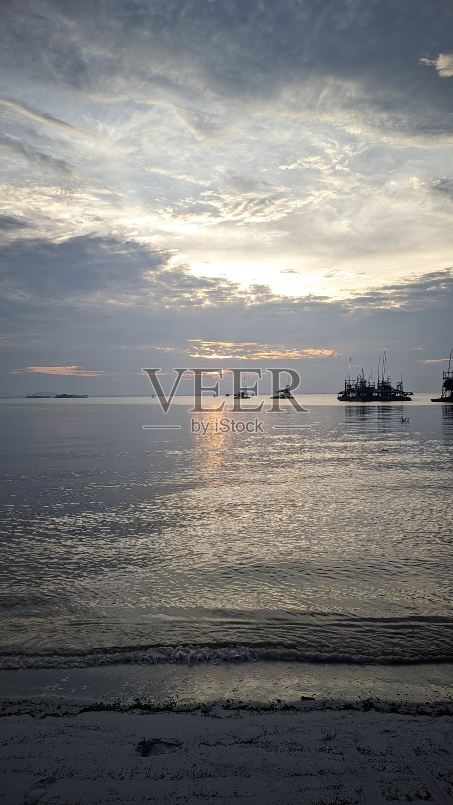 海滩上的日落景色和几艘船出现在最后照片摄影图片