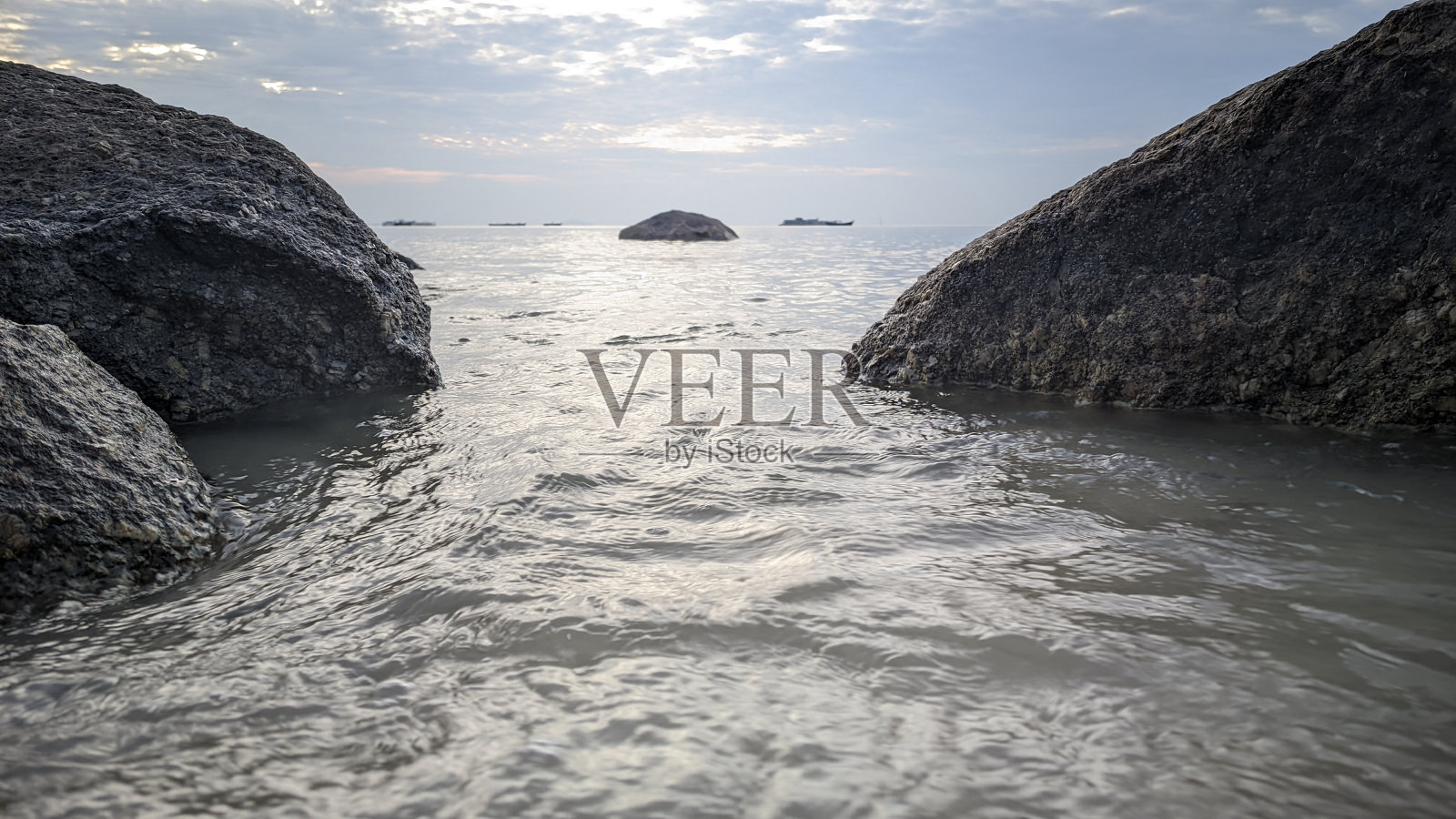 海滩上的水波和岩石涌来照片摄影图片