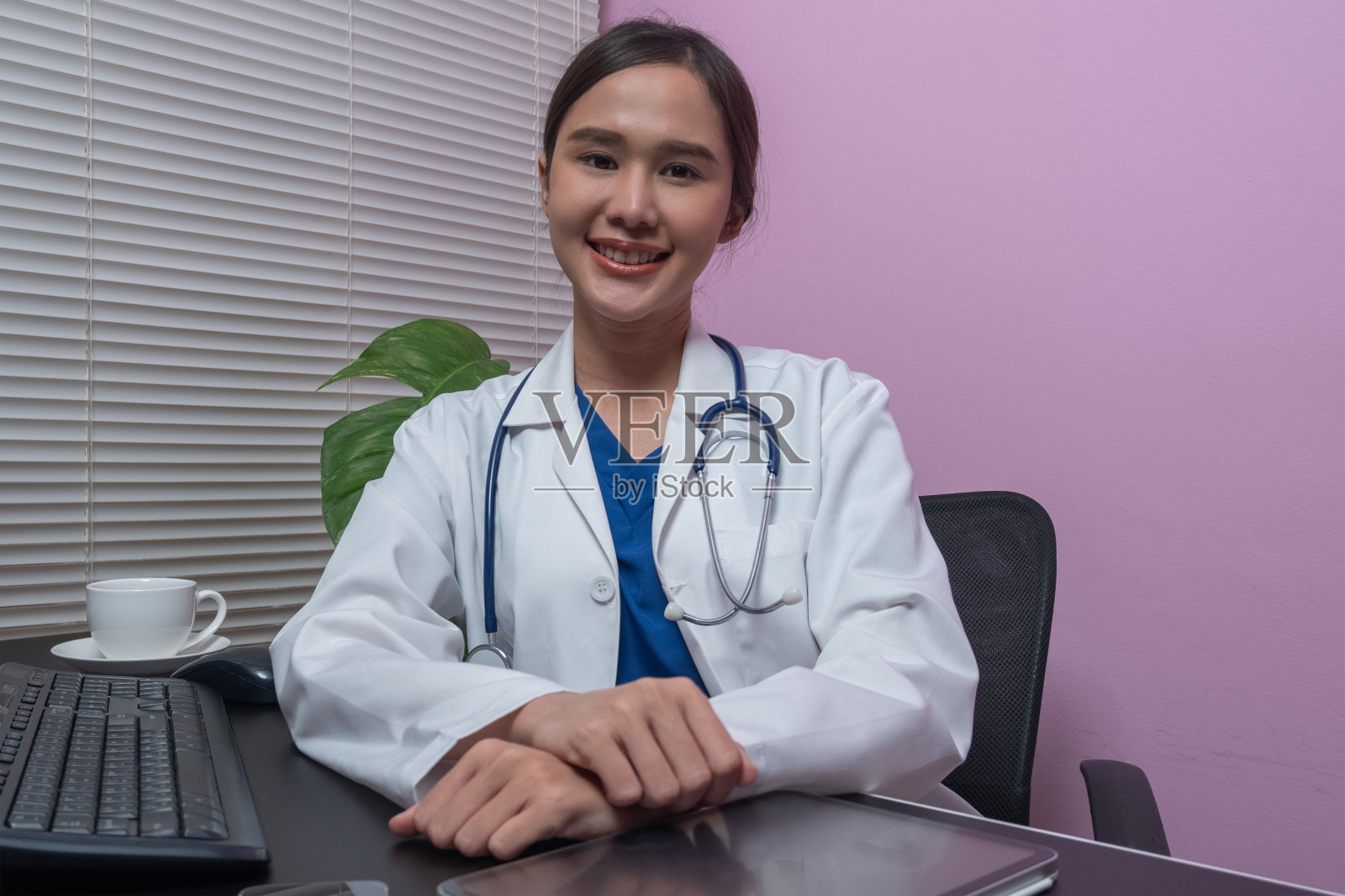 一位亚洲美女坐在诊所的房间里用电脑搜索信息，发送电子邮件。照片摄影图片