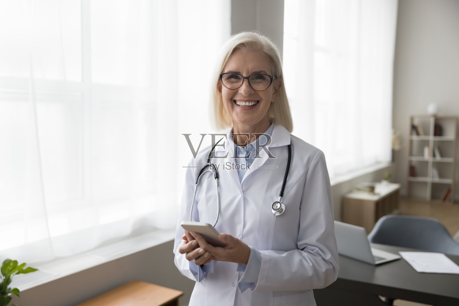 开心自信的资深女医生拿着手机照片摄影图片