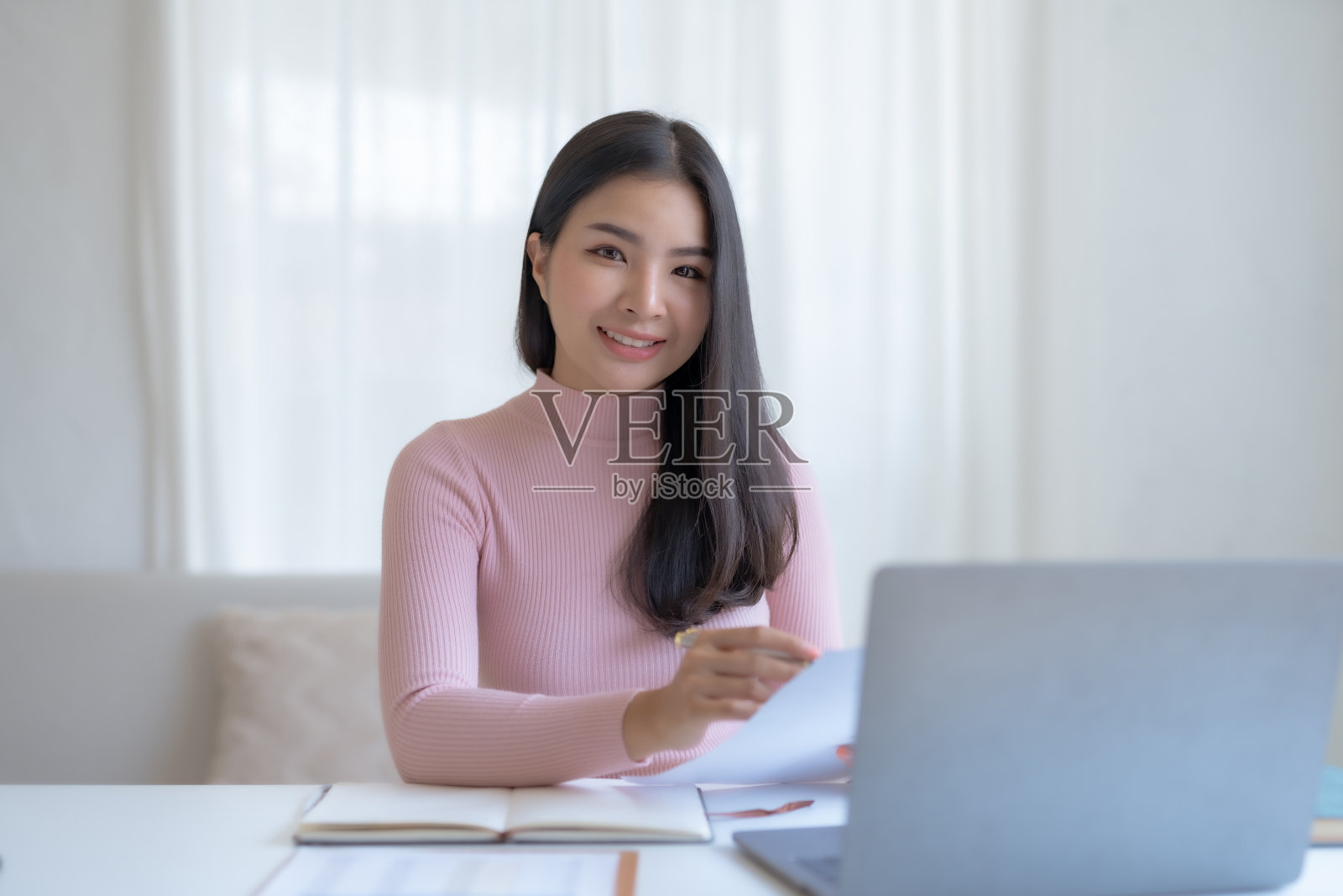 微笑快乐的亚洲女商人坐在办公室用笔记本电脑做笔记。照片摄影图片