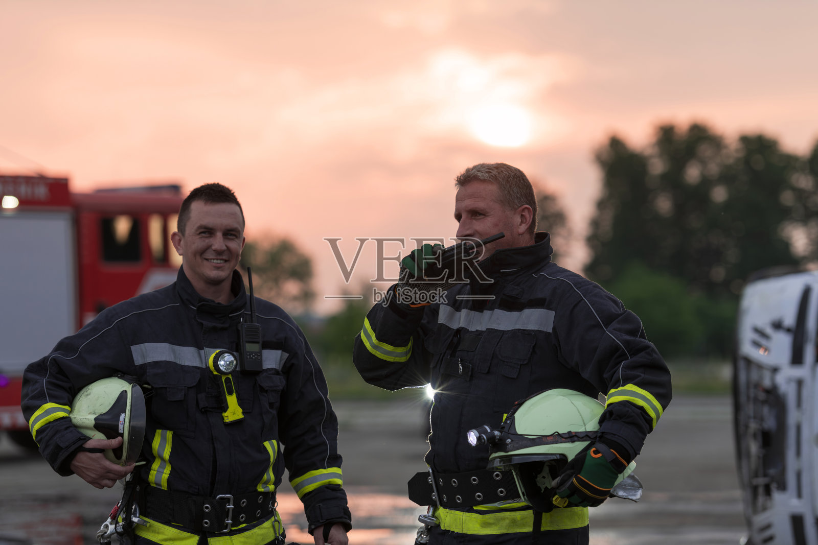 消防队员在救援行动中使用对讲机，消防车和消防队员在后台。照片摄影图片