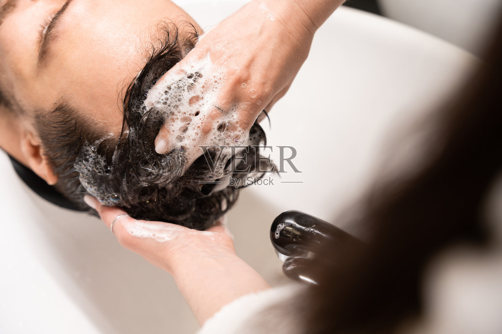 发廊里的理发师正在给一个男人洗头照片摄影图片