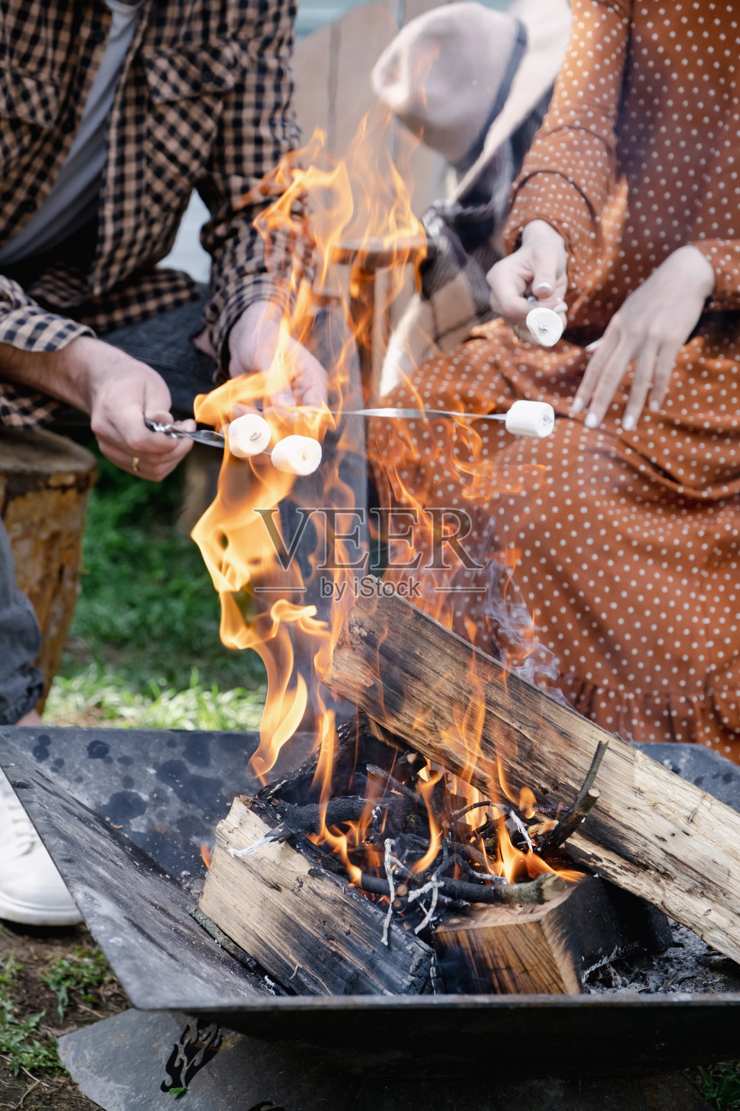 男人和女人在篝火上烤棉花糖。一对夫妇在旅行货车旁休息照片摄影图片