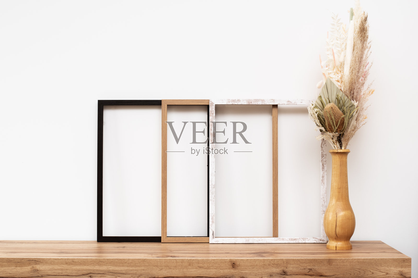 装饰靠墙的木制相框，用装饰花装饰木制抽屉柜。照片摄影图片