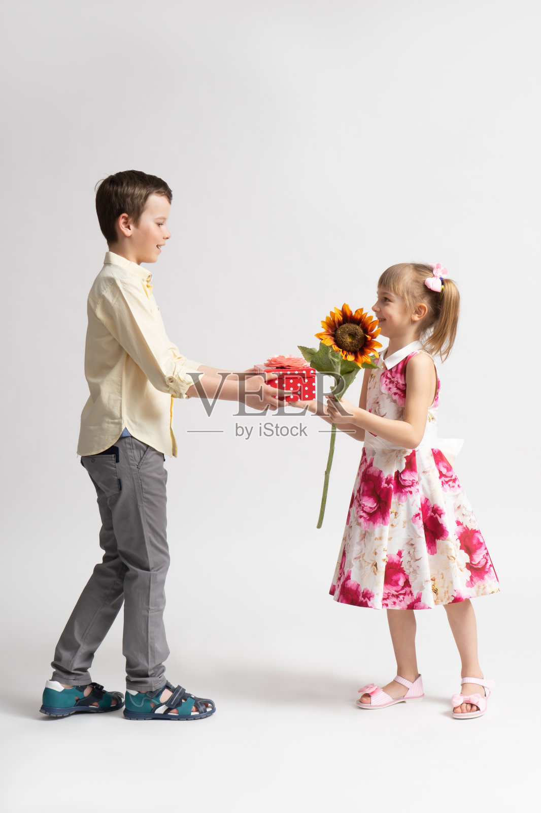 大男孩表示祝贺，并送给小女孩一份节日礼物。照片摄影图片