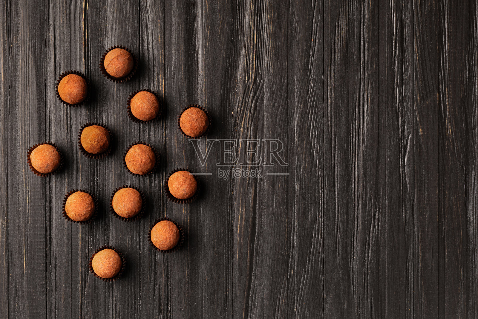 巧克力松露在单独的纸篓在一个黑暗的木制背景，俯视图，复制空间。照片摄影图片