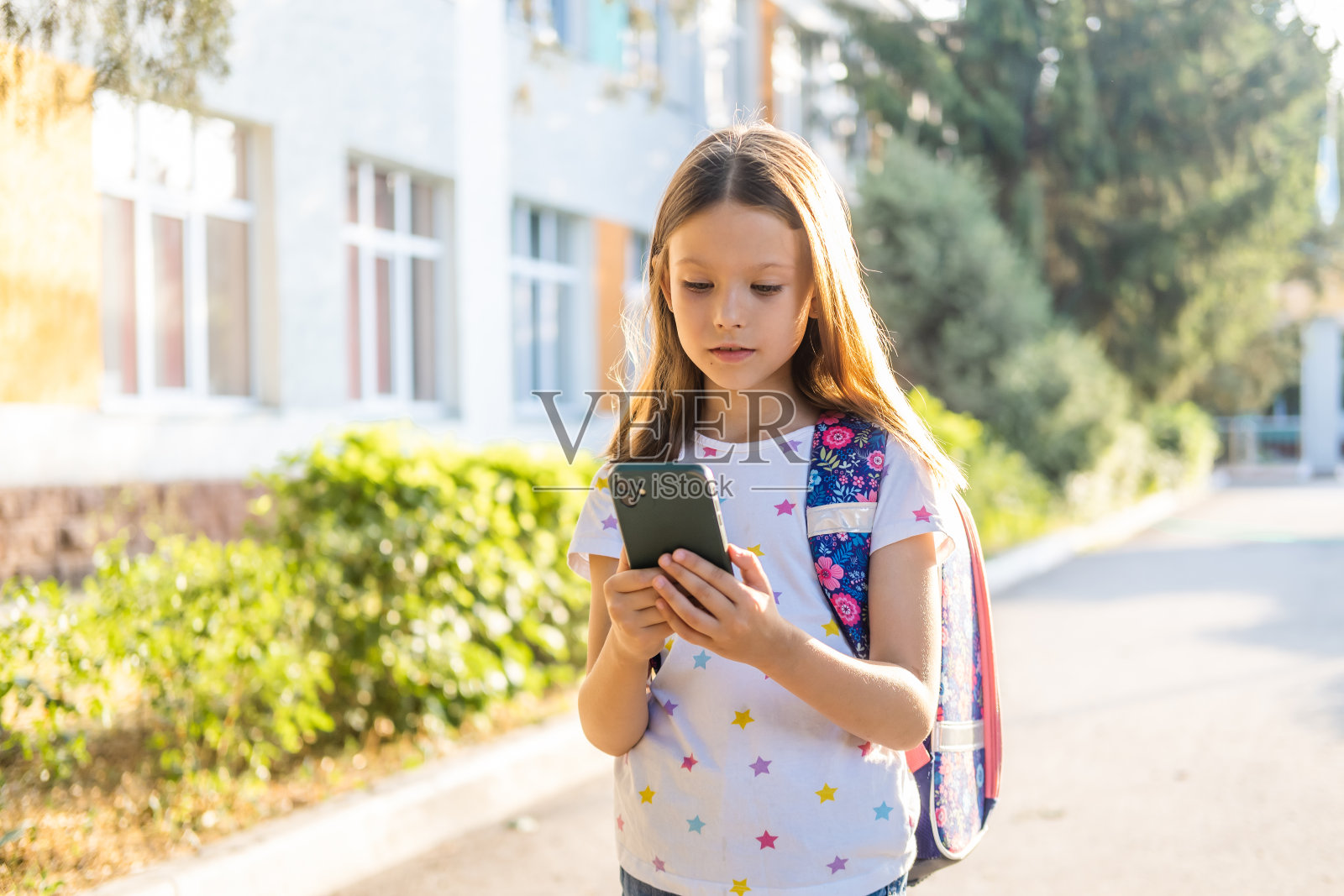 可爱的女学生背着背包使用智能手机照片摄影图片