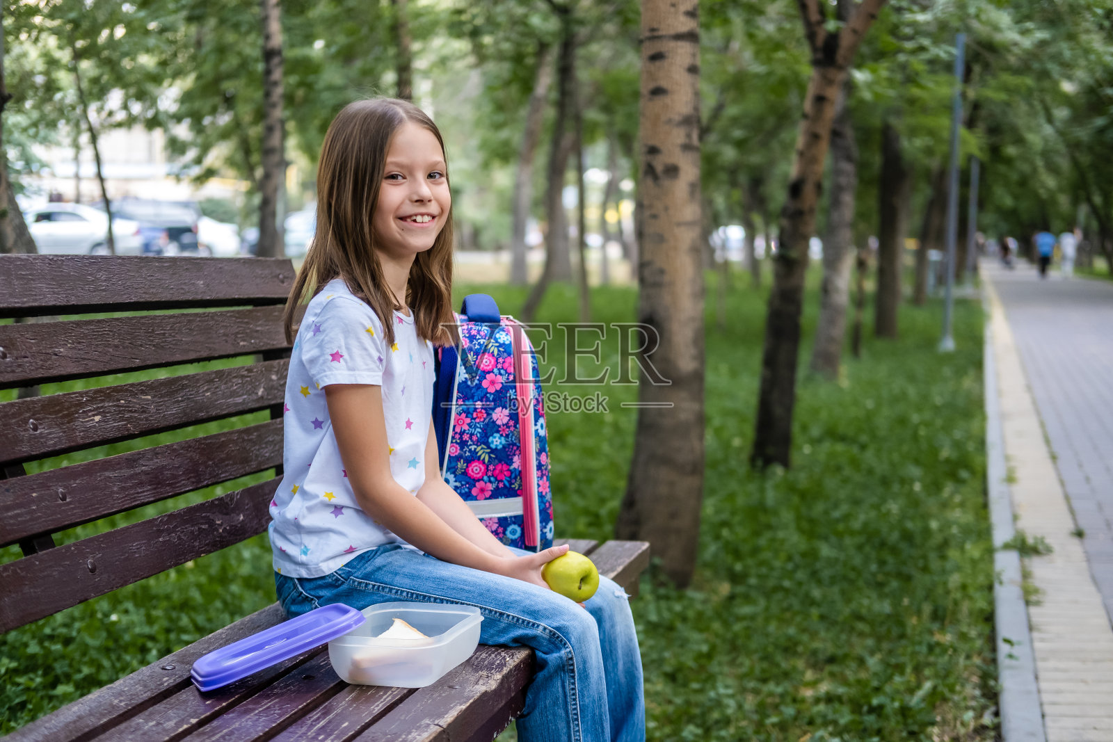 在公园里吃午餐三明治和苹果的女学生照片摄影图片