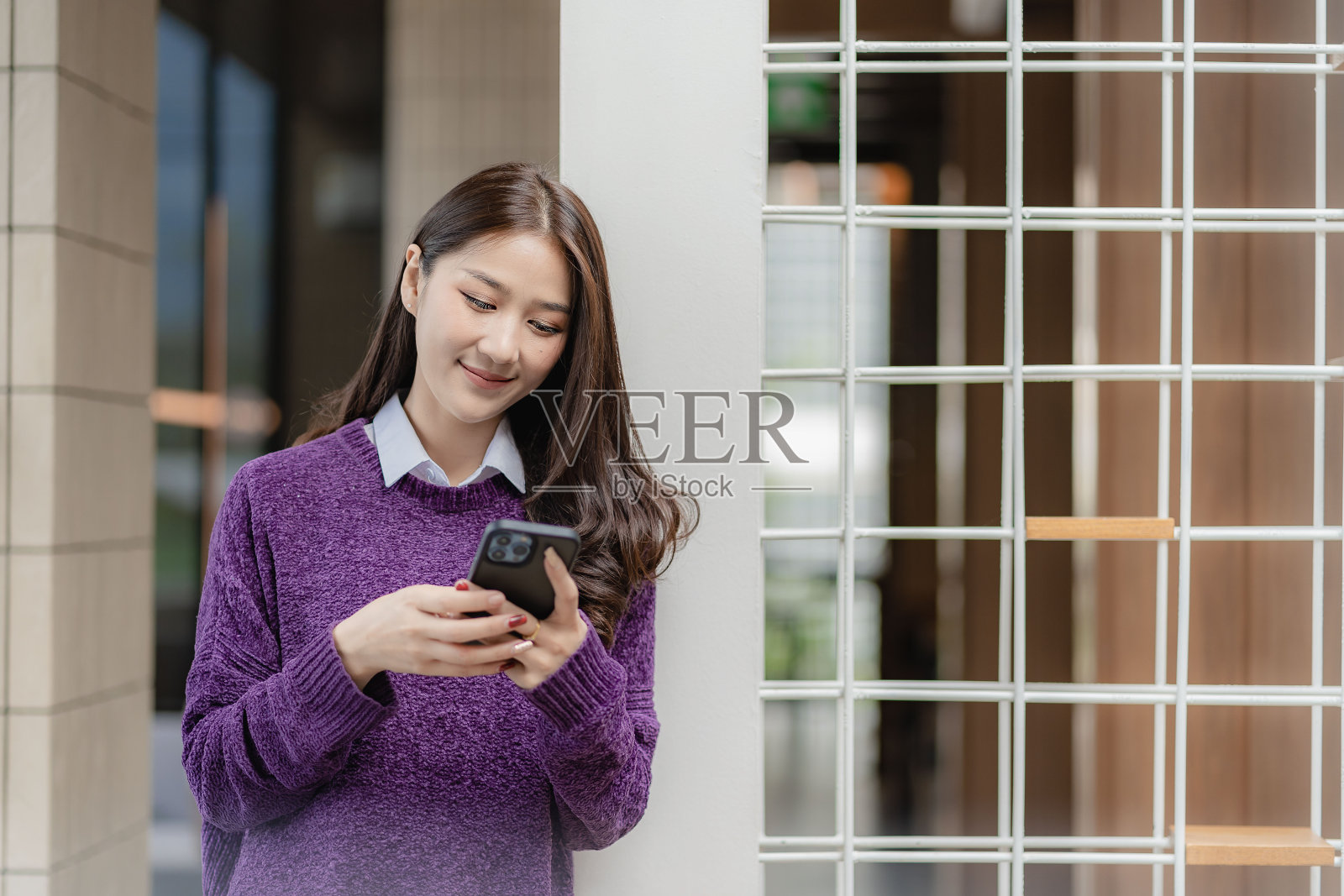 美丽成功的亚洲女商人拿着手机，在办公室用智能手机和商业模特聊天照片摄影图片
