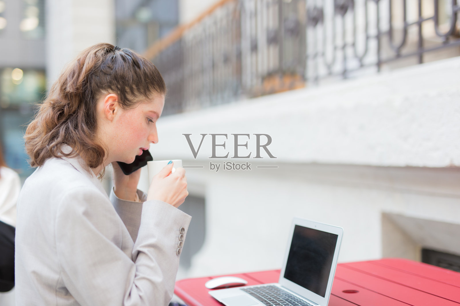 年轻的女商人一边喝咖啡一边用笔记本电脑照片摄影图片