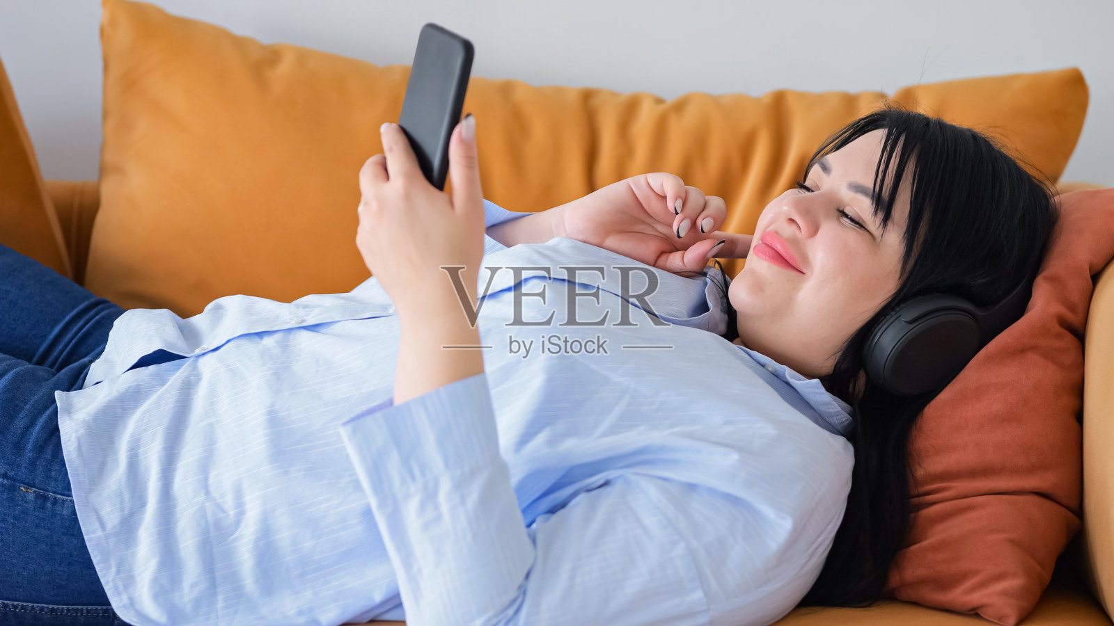 戴耳机的女人在智能手机上打开音乐播放列表照片摄影图片