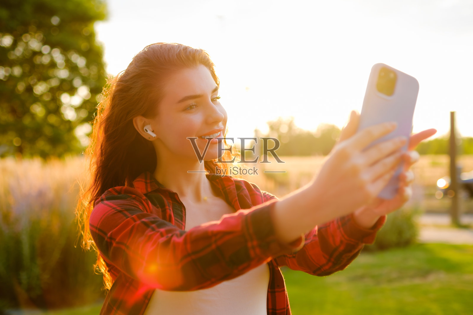 漂亮的红卷发站在街上用智能手机自拍。照片摄影图片