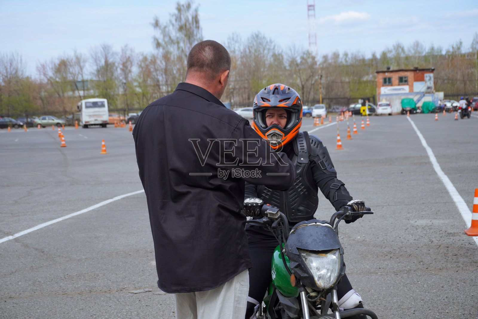 一位年轻女子在摩托车学校学习骑摩托车。她由一位老师教照片摄影图片