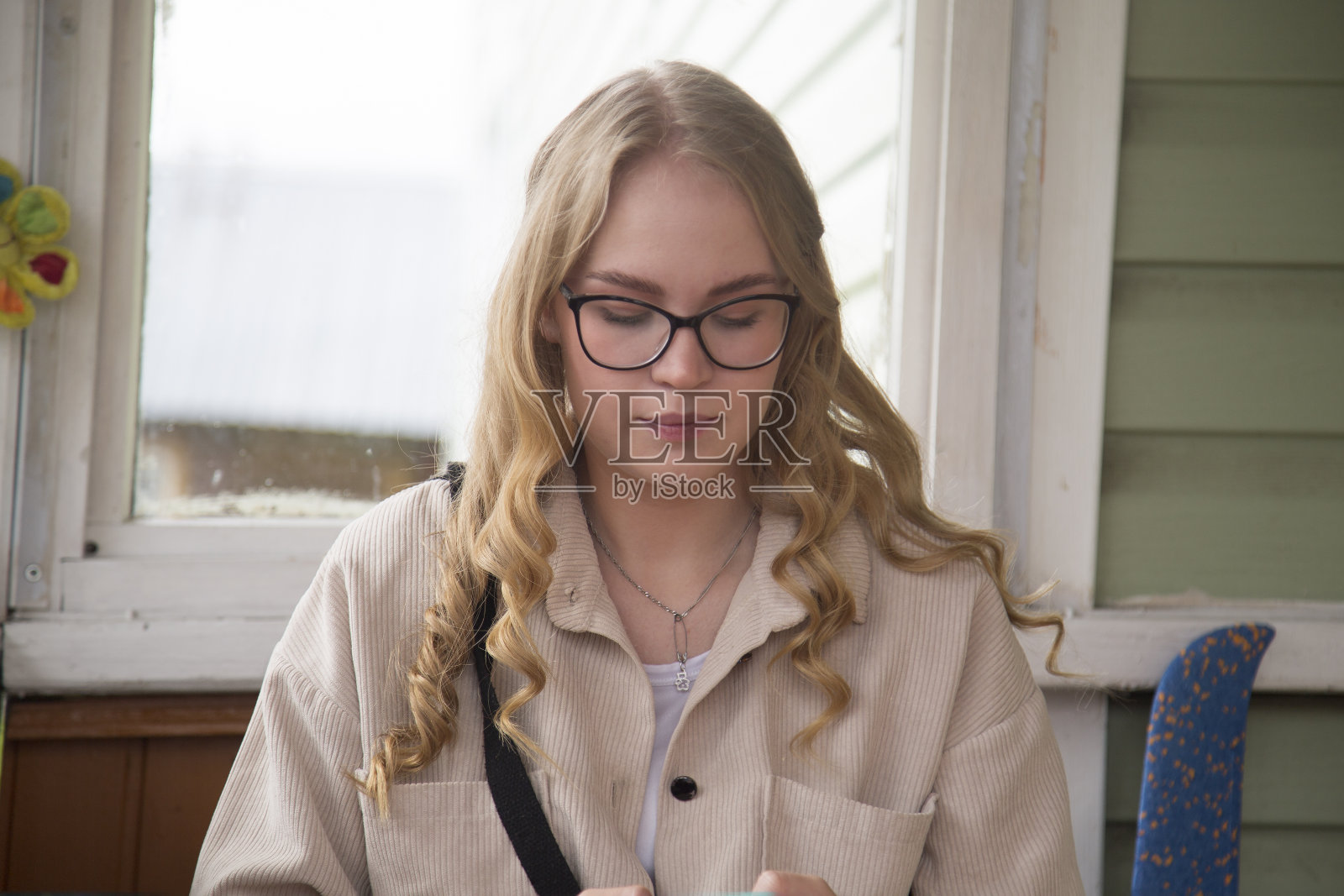 一个戴着眼镜拿着智能手机的金发美女在街上的肖像。照片摄影图片