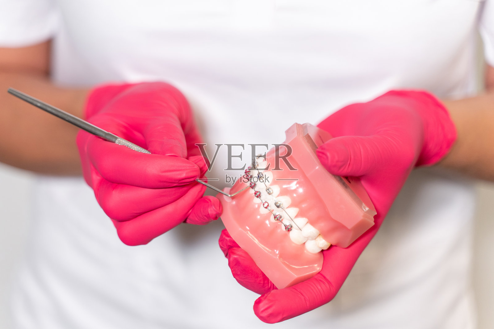 特写:牙医手戴医用手套，用塞子握住石膏，向病人描述治疗方法。口腔卫生正畸治疗照片摄影图片