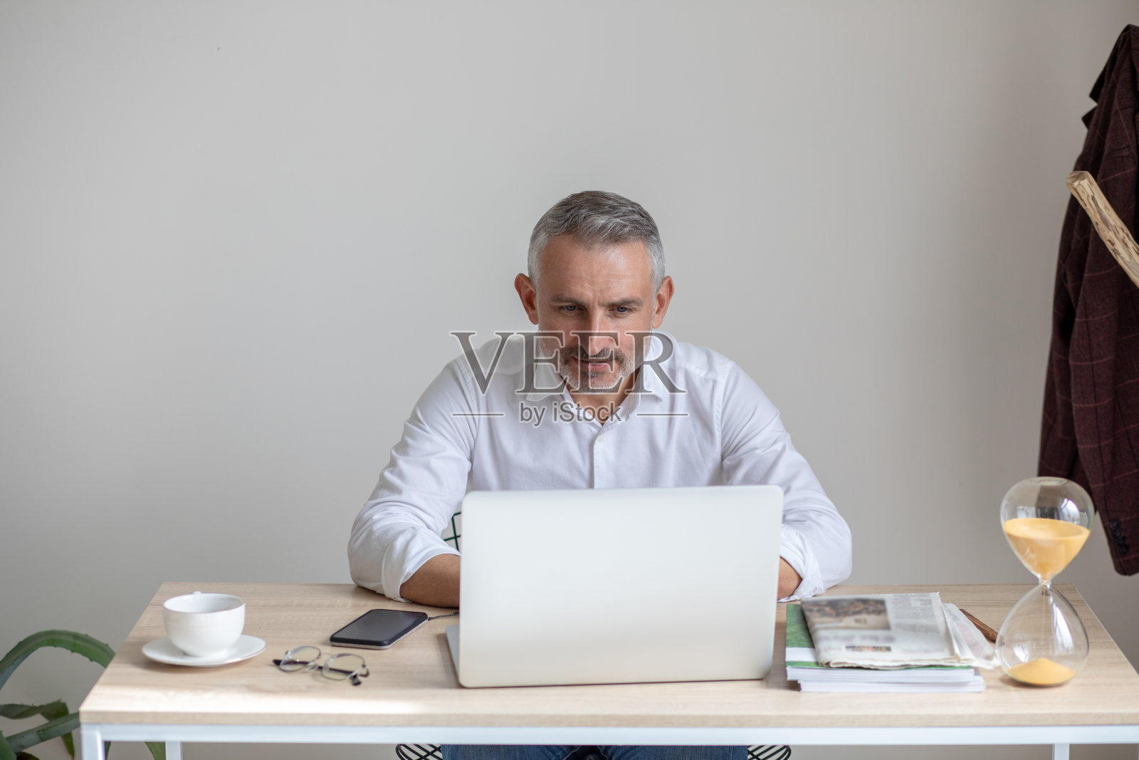 男人坐在桌子旁，目不转睛地盯着笔记本电脑屏幕照片摄影图片