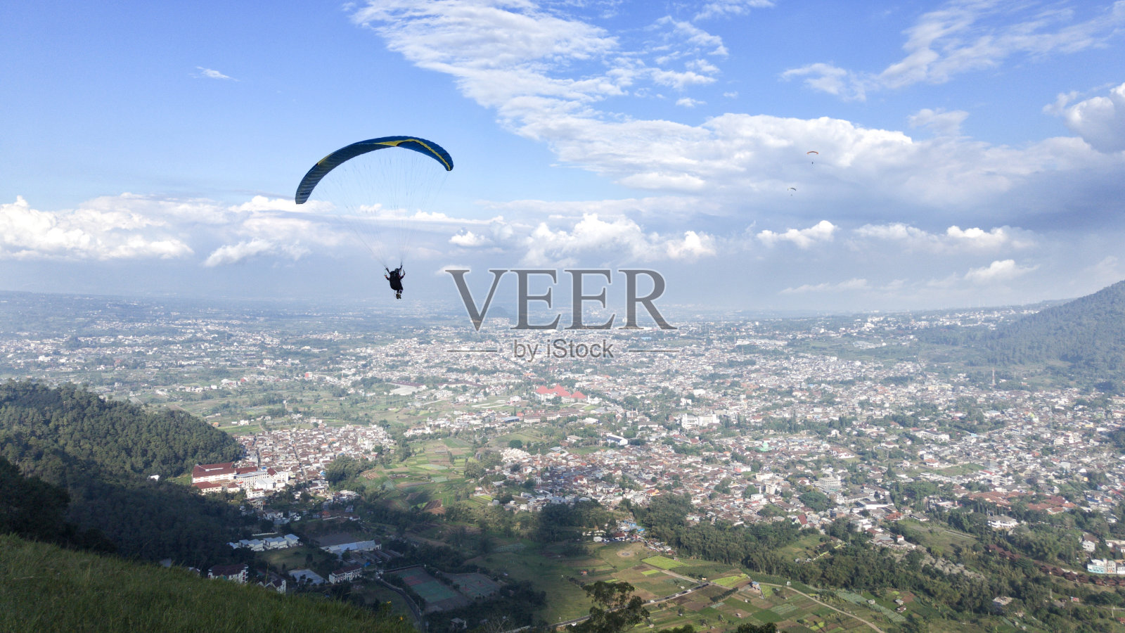 滑翔伞飞行高于村庄的看法和蓝天背景照片摄影图片