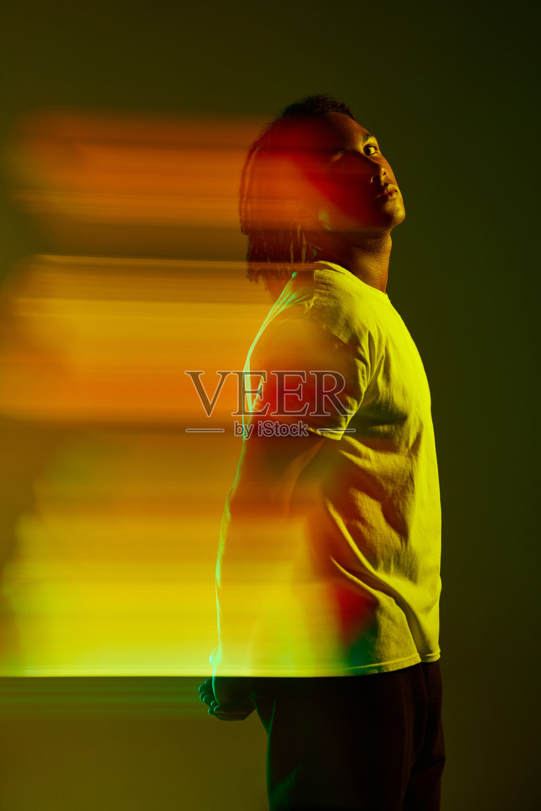 在霓虹灯的渐变绿色背景下，英俊的年轻人的肖像。混合光效果。数字化照片摄影图片