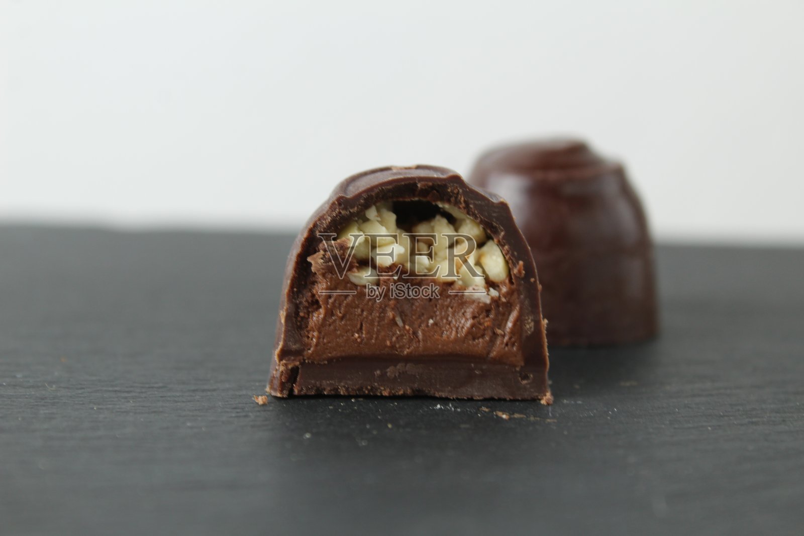 灰色黑色背景上有巧克力馅果仁甘纳许和碎花生的巧克力盒糖果。一天吃巧克力糖果，不节食照片摄影图片