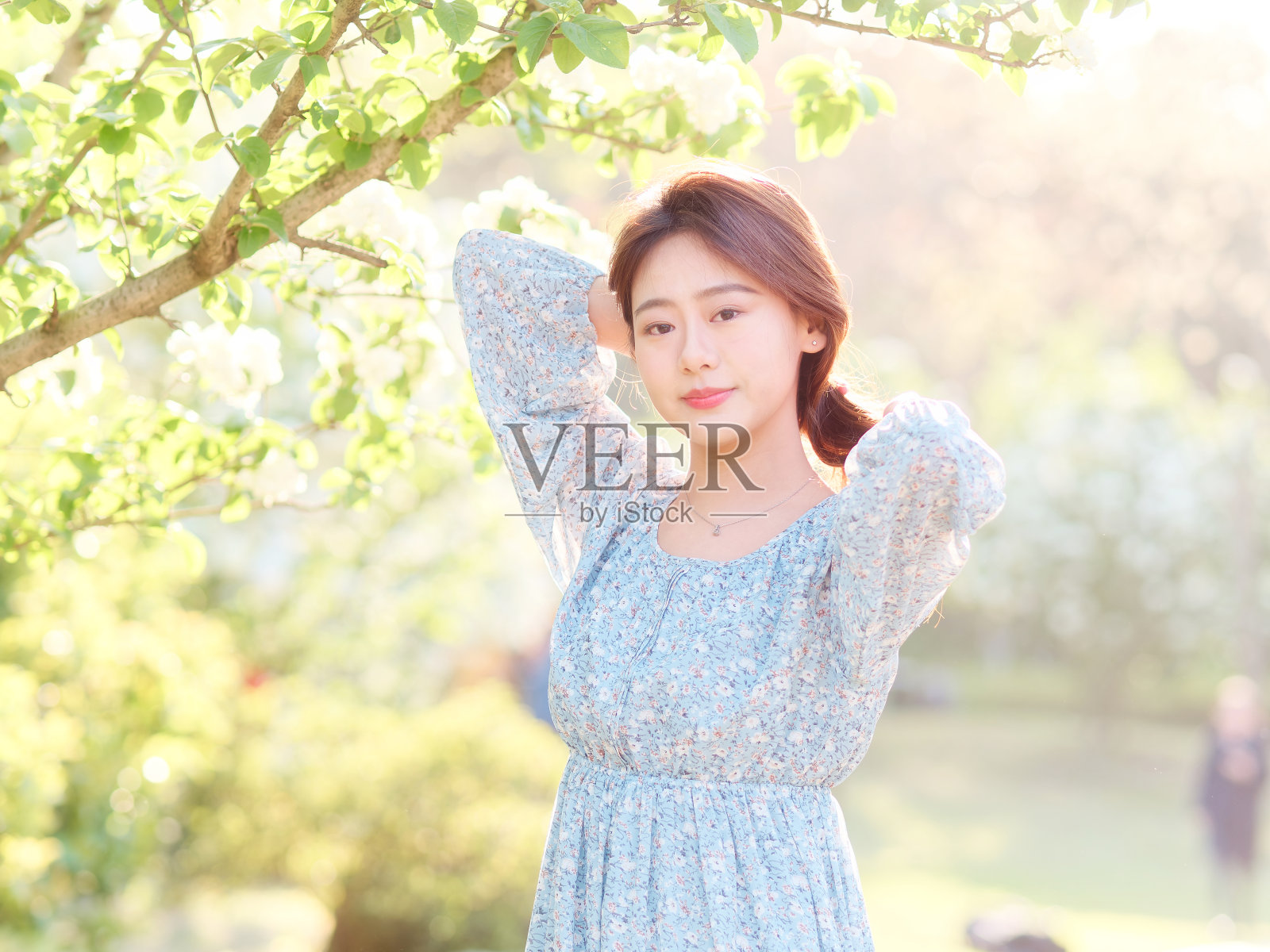 在阳光灿烂的日子里，穿着优雅的中国女孩在森林公园享受无忧无虑的时光。户外时尚肖像的魅力年轻的中国开朗的时尚女性。照片摄影图片