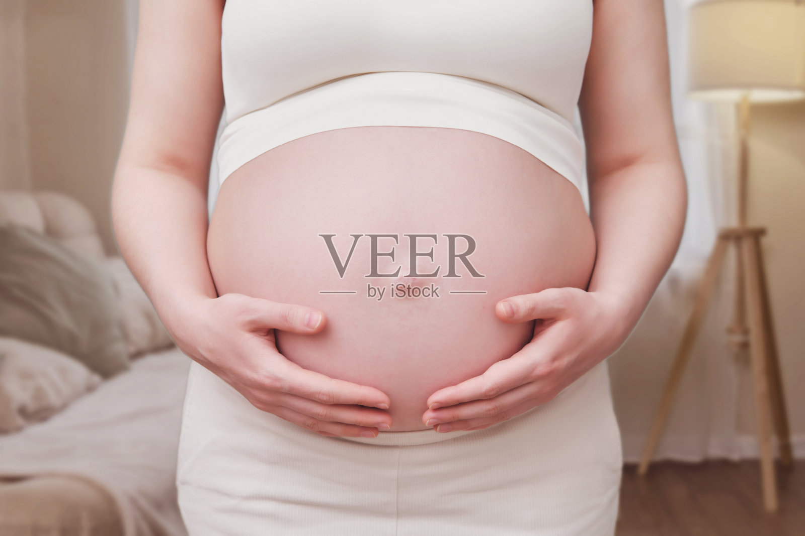 手放在孕妇肚子上，家里客厅照片摄影图片