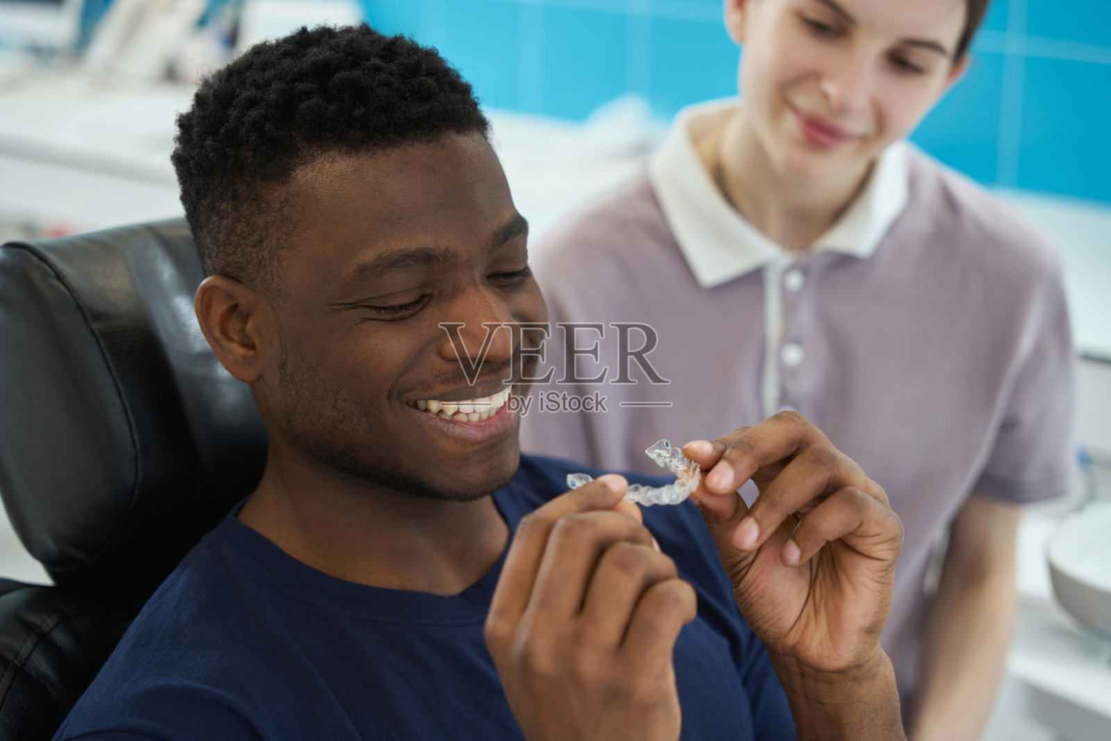 戴着透明牙套的非裔美国人顾客在牙科诊所就诊照片摄影图片
