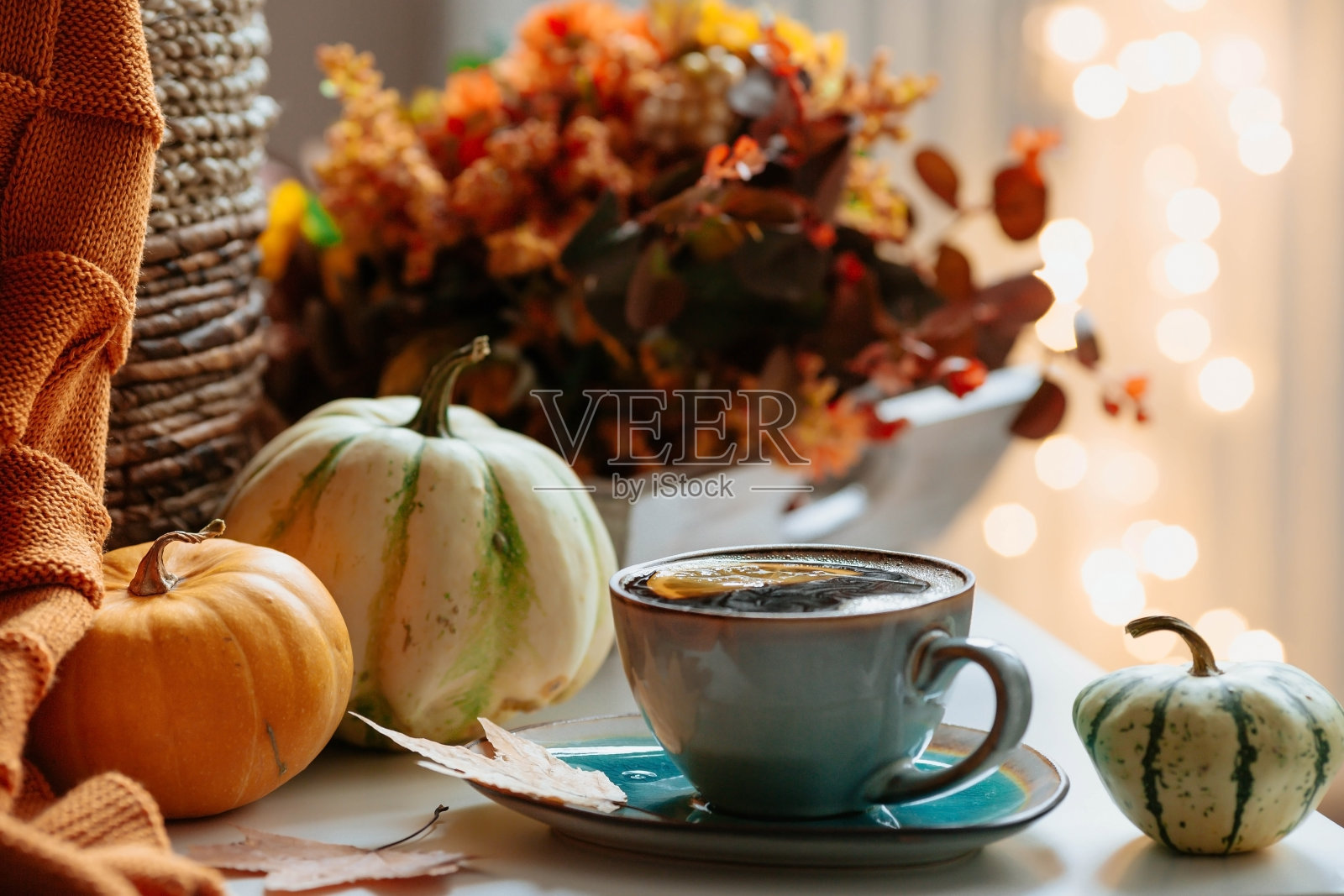 静物。客厅里的咖啡桌上放着一条毯子、南瓜和一杯茶。一个舒适的秋季概念。照片摄影图片
