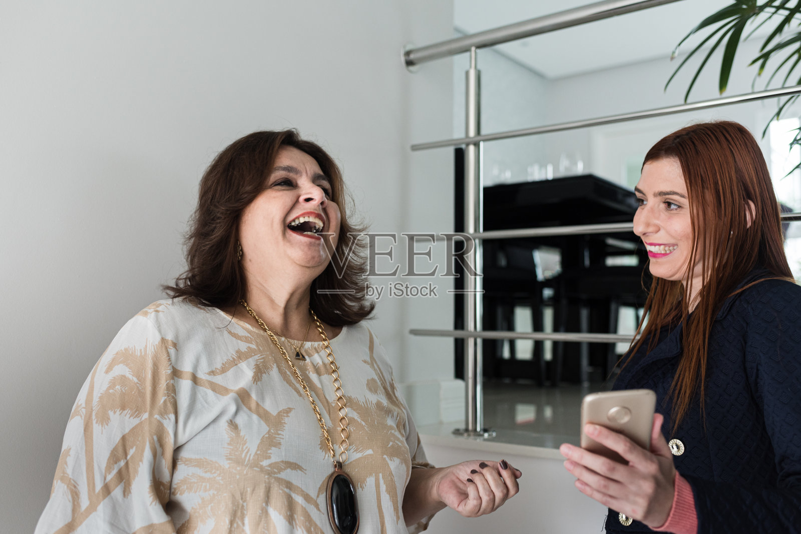 微笑的母亲和女儿在家里用智能手机照片摄影图片