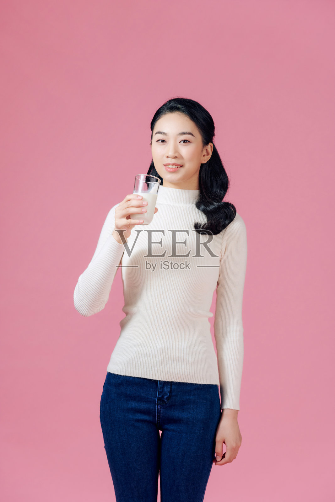 可爱健康的女人正在喝牛奶从玻璃隔离在粉红色的背景。照片摄影图片