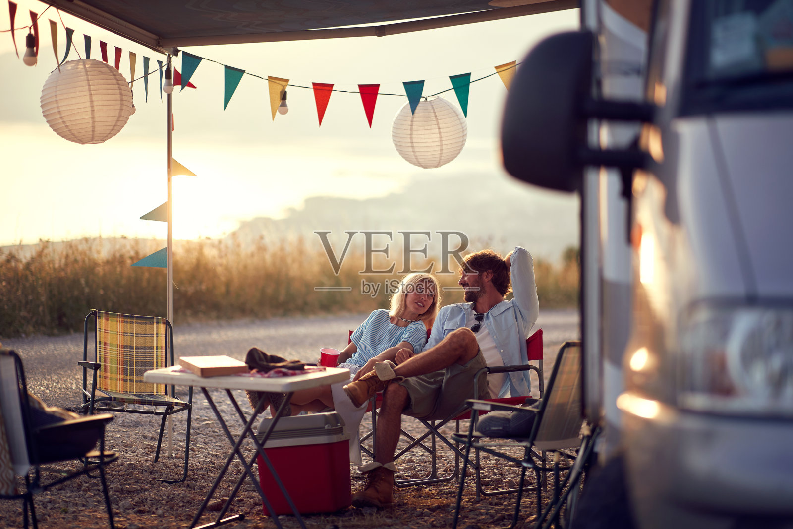 一对年轻夫妇坐在野外的露营地聊天。恋爱，度假，野营，自然照片摄影图片