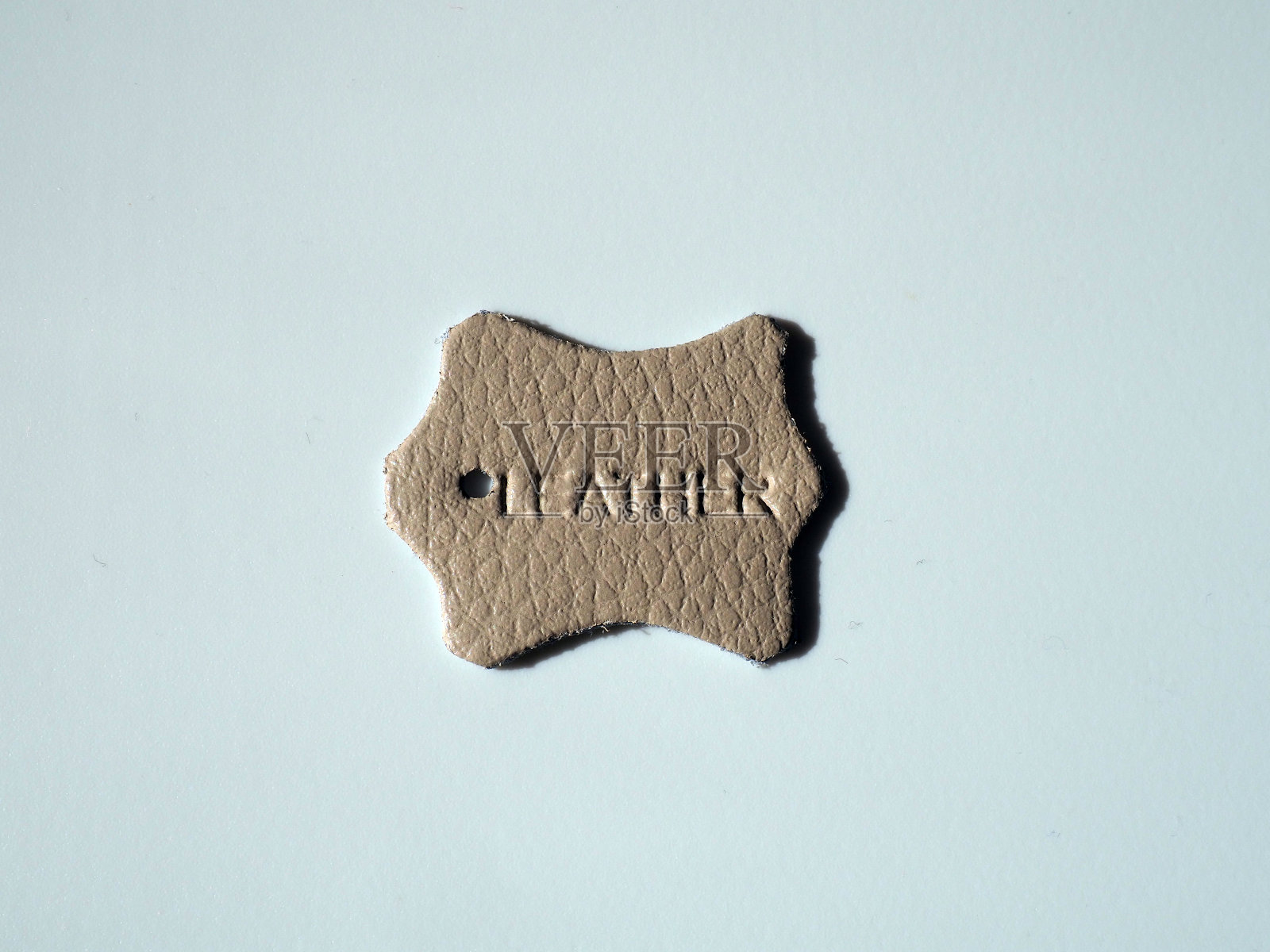 皮革标签或标签上的白色背景。前视图。铭文皮革压印在材料的表面。白色背景,影子。皮革制品制造。水平的质量照片摄影图片